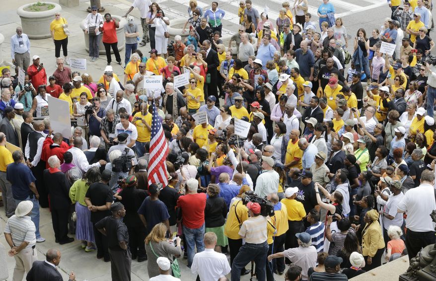 Protesters congregate in front of city hall Tuesday, May 26, 2015, in Cleveland. Members of about 40 churches are protesting the acquittal of a white patrolman charged in the deaths of two unarmed black motorists with a march through downtown Cleveland. (AP Photo/Tony Dejak)