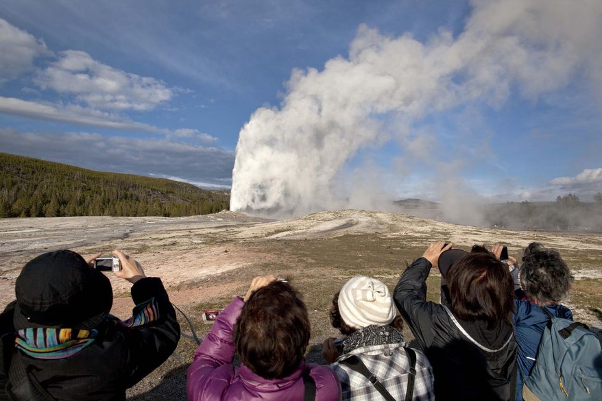 FILE - In this Saturday, May 21, 2011 file photo, tourists photograph Old Faithful erupting on schedule late in the afternoon in Yellowstone National Park, Mont. Lower gas prices and other indicators point to plenty of out-of-state visitors coming to Wyoming to enjoy national parks and other attractions this summer, tourism officials say. (AP Photo/Julie Jacobson, File)