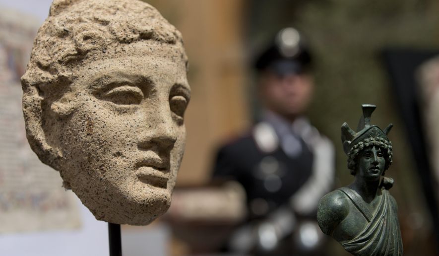 A third century B.C. terracotta head, left, and a second century Roman bronze figure representing Mars, are shown during a press conference in Rome, Tuesday, May 26, 2015. The United States has returned 25 artifacts that were looted from Italy, including Etruscan vases, 1st century frescoes and precious books that had made their way into top-notch U.S. museum, university and private collections. (AP Photo/Alessandra Tarantino)