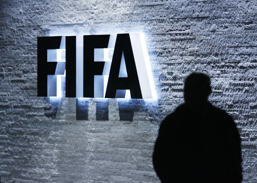 FILE - In this Oct. 29, 2007 file photo, a person stands next to the FIFA logo at the FIFA headquarter in Zurich, Switzerland. The Swiss Federal Office of Justice said six soccer officials have been arrested and detained pending extradition at the request of U.S. authorities ahead of the FIFA congress in Zurich. In a statement Wednesday, May 27, 2015, the FOJ said U.S. authorities suspect the officials of having received paid bribes totaling millions of dollars. (Steffen Schmidt/Keystone via AP, File)