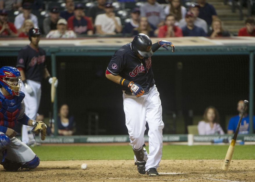 Cleveland Indians' Carlos Santana reacts after being hit on the hand by a pitch from Texas Rangers' Shawn Tolleson, as Rangers catcher Carlos Corporan watches during the ninth inning of a baseball game in Cleveland, Tuesday, May 26, 2015. The Rangers won 4-3. (AP Photo/Phil Long)