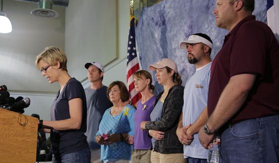 Kellye Burke, left, speaks on behalf of families of the victims of recent severe weather at a news conference, Thursday, May 28, 2015, in Wimberley, Texas. Listening to Burke, background from left, are Mark Combs, Marry Ann Charba, Kim Charba, Cristen Daniel, Justin McComb and and Jeff Schults. The storms and floods in Texas and Oklahoma this week have left at least 21 people dead and at least 10 others missing.  (AP Photo/Eric Gay)