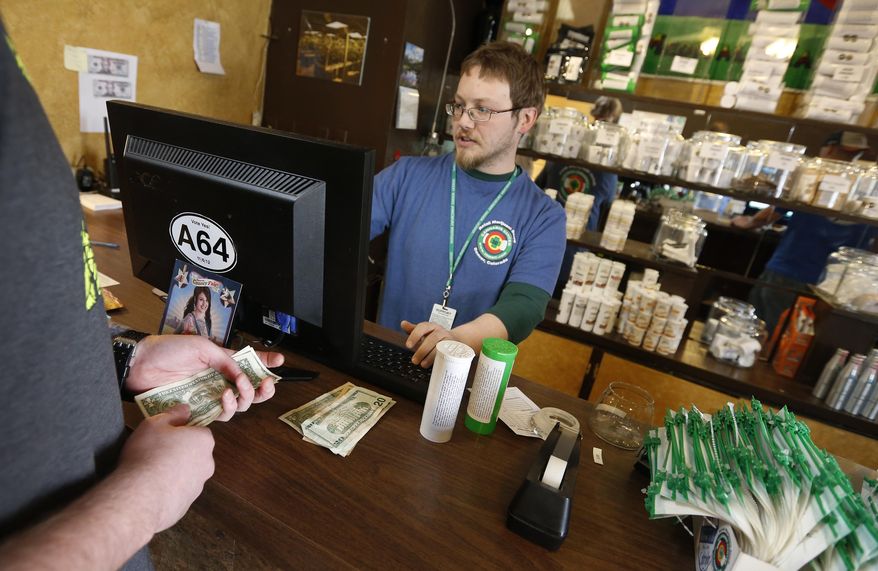 FILE - In this May 8, 2014 file photo, a customer pays cash for retail marijuana at 3D Cannabis Center, in Denver. Three suburban Denver cities are suing Adams County to stop it from collecting taxes from marijuana businesses already being taxed by the cities. At issue is a voter-approved 3 percent sales tax in Adams County that takes effect July 1. (AP Photo/Brennan Linsley, file)