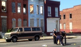 Police pick up a pair of shoes after a double shooting in Baltimore in this May 24, 2015, file photo. (Colin Campbell/The Baltimore Sun via AP, File)