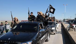 In this photo released on May 4, 2015, by a militant website, which has been verified and is consistent with other AP reporting, Islamic State militants pass by a convoy in Tel Abyad town, northeast Syria. In contrast to the failures of the Iraqi army, in Syria Kurdish fighters are on the march against the Islamic State group, capturing towns and villages in an oil-rich swath of the country&#39;s northeast in recent days, under the cover of U.S.-led airstrikes. (Militant website via AP)