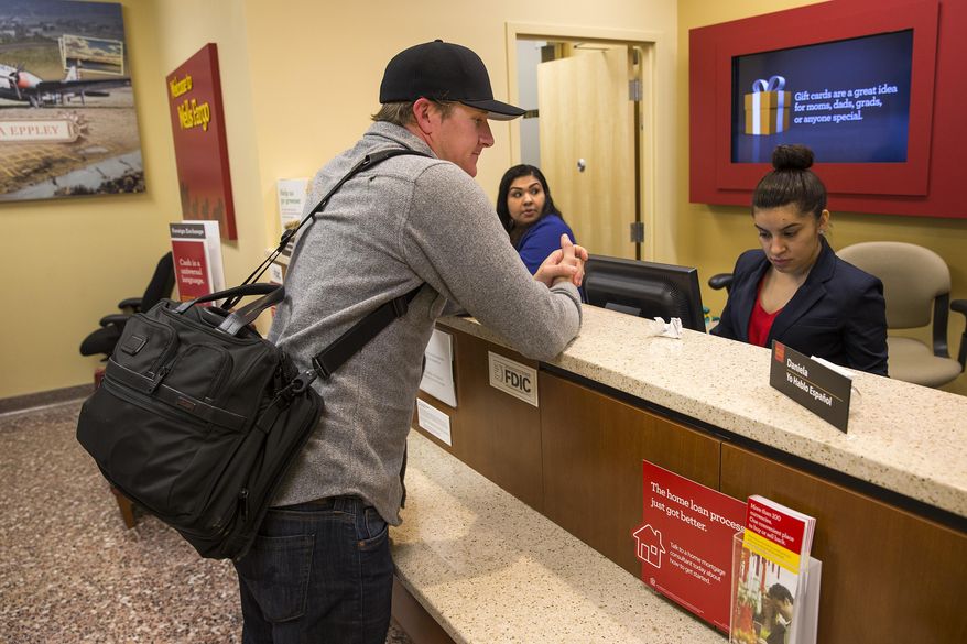 ADVANCE FOR RELEASE SUNDAY, MAY 31, 2015 Jon Urbana of Denver, works with teller Daniela Garcia, of Omaha on Tuesday, May 26, 2015, in Omaha, Neb. The branch features an assisted service ATM which caters to lots of options for customers within the small space branch. (Brendan Sullivan/The World-Herald via AP)