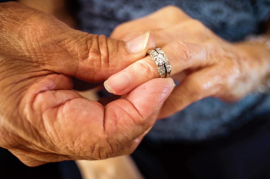 Robert Kirker puts a wedding ring, lost for 30 years, on his wife Ofelia's hand at their home in Las Cruces, N.M., May 27, 2015. It's been decades since Ofelia Kirker lost her wedding rings, but she'll be wearing the treasured jewelry for her 64th wedding anniversary. The rings were unearthed in a yard there years ago and have finally made their way back to her thanks to an observant yard worker, one woman's sharp memory and her daughter's persistence. (Jett Lowe/Las Cruces Sun-News via AP) MANDATORY CREDIT