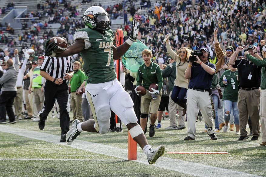File - In this Saturday, Nov. 22, 2014, file photo, UAB running back Jordan Howard (7) scores a touchdown against Marshall during the fourth quarter of an NCAA college football game, in Birmingham, Ala. UAB president Ray Watts is bringing the football program back. He told The Associated Press that he decided on Monday, June 1, 2015 to reverse the earlier decision after meetings with UAB supporters continued through the weekend. He says donors have pledged to make up the estimated $17.2 million deficit over the next five years if football is restored. (AP Photo/John Amis, file)