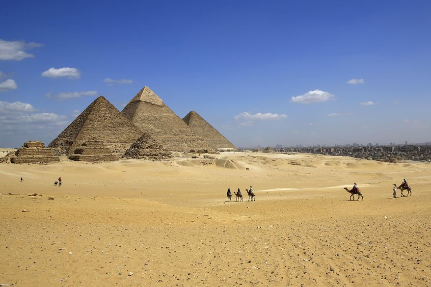 FILE - In this Thursday, April 9, 2015, file photo, tourists ride camels at the historical site of the Giza Pyramids in Giza, near Cairo, Egypt. Gunmen on a speeding motorcycle opened fire outside the plateau of the famed Giza Pyramids on the outskirts of Cairo early Wednesday, killing two policemen, in a rare attack near the country’s tourist attractions, Egypt’s state news agency and security officials said. (AP Photo/Hassan Ammar)