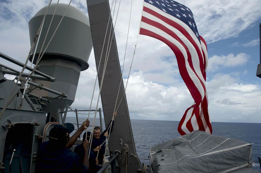 FILE - In this June 28, 2014 file photo, U.S. Navy personnel raise their national flag during the bilateral maritime exercise between the Philippine Navy and U.S. Navy, dubbed Cooperation Afloat Readiness and Training (CARAT) aboard the USS John S. McCain in the South China Sea near waters claimed by Beijing. The dispute over the strategic waterways of the South China Sea has intensified, pitting a rising China against its smaller and militarily weaker neighbors who all lay claim to a string of isles, coral reefs and lagoons known as the Spratly and the Paracel islands. The U.S. military has begun actively - and more publicly - challenging China’s sovereignty claims over half a dozen artificial islands Beijing has been rapidly constructing through massive land reclamation. (Noel Celis/Pool Photo via AP, File)