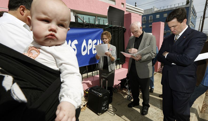This file photo taken March 5, 2014, shows 7-month-old Abigail Dalton of Ridgeland, seeming to be listening as state Mississippi Sen. Chris McDaniel, R-Ellisville, right, prays with fellow abortion opponents, Laura Duran of Pro-Life Mississippi, left, and Rev. Mike O'Brien, pastor of St. Richard Catholic Church in Jackson, center, outside the Jackson Women's Health Organization clinic in Jackson, Miss., during the first day of a 40-day pro-life mobilization outside the only facility in the state that still performs abortions. Abortions have declined in states where new laws make it harder to have them - but they've also waned in states where abortion rights are protected, an Associated Press survey finds. Nearly everywhere, in red states and blue, abortions are down since 2010. (AP Photo/Rogelio V. Solis)