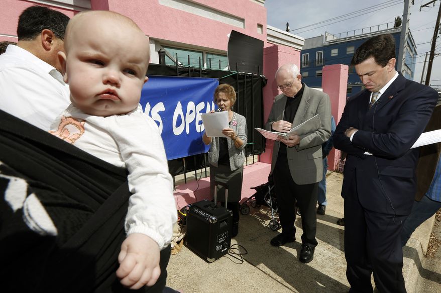This file photo taken March 5, 2014, shows 7-month-old Abigail Dalton of Ridgeland, seeming to be listening as state Mississippi Sen. Chris McDaniel, R-Ellisville, right, prays with fellow abortion opponents, Laura Duran of Pro-Life Mississippi, left, and Rev. Mike O'Brien, pastor of St. Richard Catholic Church in Jackson, center, outside the Jackson Women's Health Organization clinic in Jackson, Miss., during the first day of a 40-day pro-life mobilization outside the only facility in the state that still performs abortions. Abortions have declined in states where new laws make it harder to have them - but they've also waned in states where abortion rights are protected, an Associated Press survey finds. Nearly everywhere, in red states and blue, abortions are down since 2010. (AP Photo/Rogelio V. Solis)