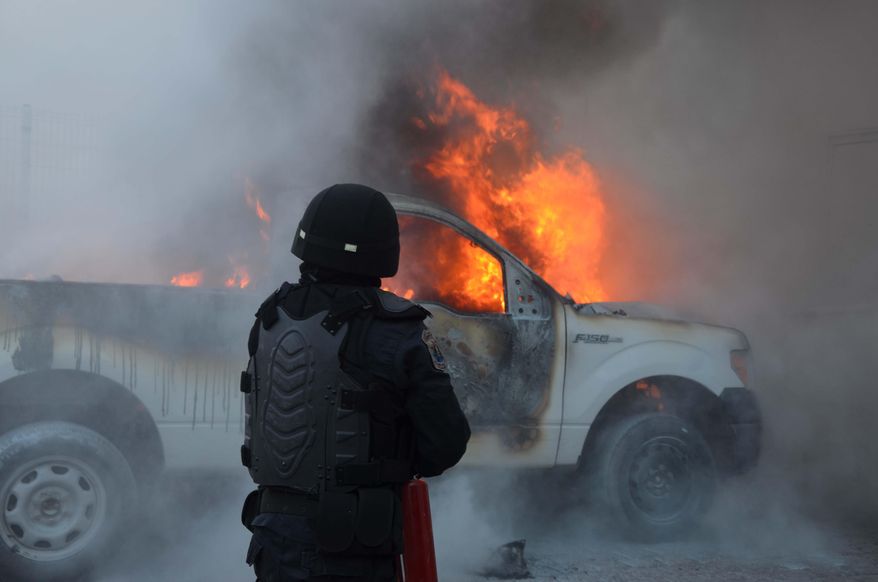 A riot policeman use extinguishers to put out the flames of a burning pick-up truck after it was set on fire in the state capital of Chilpancingo, Guerrero state, Sunday, June 7, 2015. Next to the truck several molotov bombs were found. The incident comes on the day of the mid-term elections as a loose coalition of radical teachers' unions and activists vowed to block the vote for 500 seats in the lower house of Congress, nine of 31 governorships and hundreds of mayors and local officials. (AP Photo/Alejandrino Gonzalez)