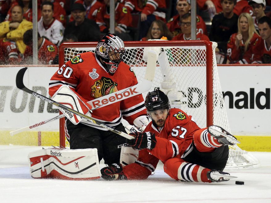 Chicago Blackhawks&#x27; Trevor van Riemsdyk, right, slides past goalie Corey Crawford while chasing after a loose puck during the third period in Game 3 of the NHL hockey Stanley Cup Final against the Tampa Bay Lightning on Monday, June 8, 2015, in Chicago. (AP Photo/Nam Y. Huh)