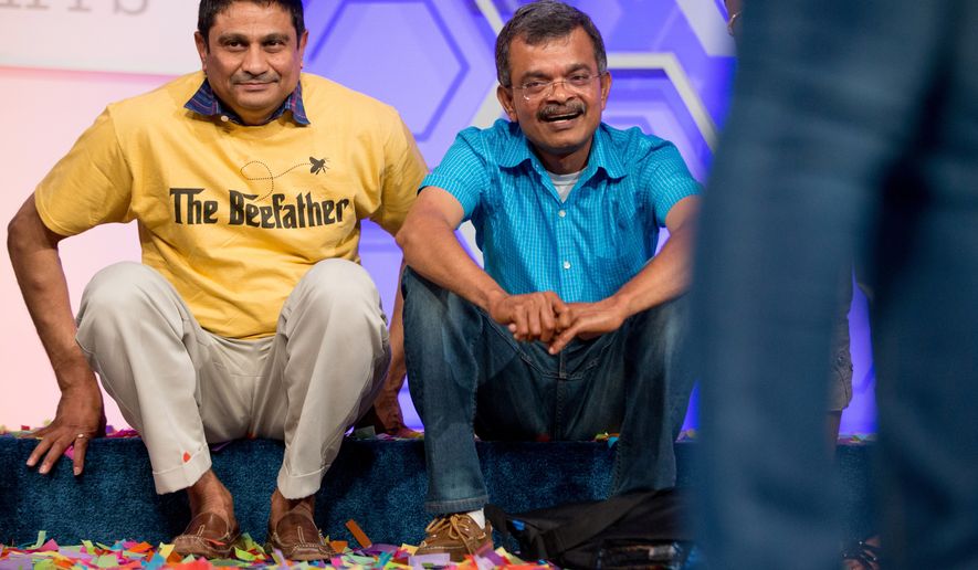Mirle, left, the father of Vanya Shivashankar, 13, of Olathe, Kan., and Krishnan, the father of Gokul Venkatachalam, 14, of St. Louis, sit onstage together after their children are named co-champions of the Scripps National Spelling Bee, Thursday, May 28, 2015, in Oxon Hill, Md. (AP Photo/Andrew Harnik)