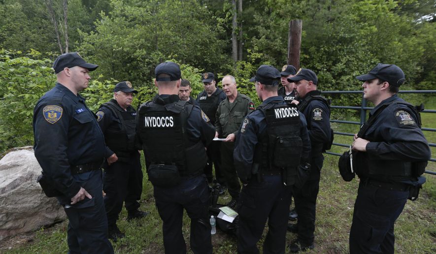 State forest ranger Dan Fox reviews a map with members of the New York State Department of Corrections and Community Supervision emergency response team before entering a wooded area in search of two prisoners who escaped from the Clinton Correctional Facility on Monday, June 8, 2015, in Dannemora, N.Y. The two murderers who escaped from the prison by cutting through steel walls and pipes remain on the loose Monday as authorities investigate how the inmates obtained the power tools used in the breakout. (AP Photo/Mike Groll)