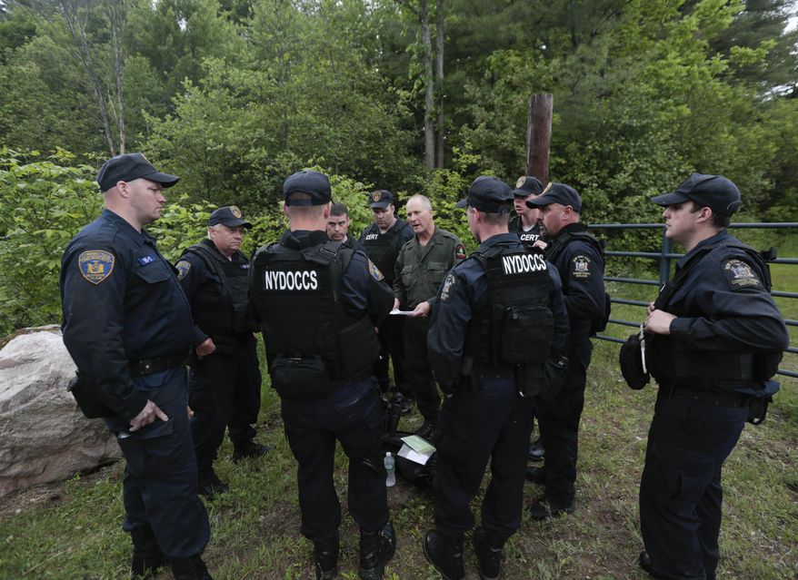 State forest ranger Dan Fox reviews a map with members of the New York State Department of Corrections and Community Supervision emergency response team before entering a wooded area in search of two prisoners who escaped from the Clinton Correctional Facility on Monday, June 8, 2015, in Dannemora, N.Y. The two murderers who escaped from the prison by cutting through steel walls and pipes remain on the loose Monday as authorities investigate how the inmates obtained the power tools used in the breakout. (AP Photo/Mike Groll)