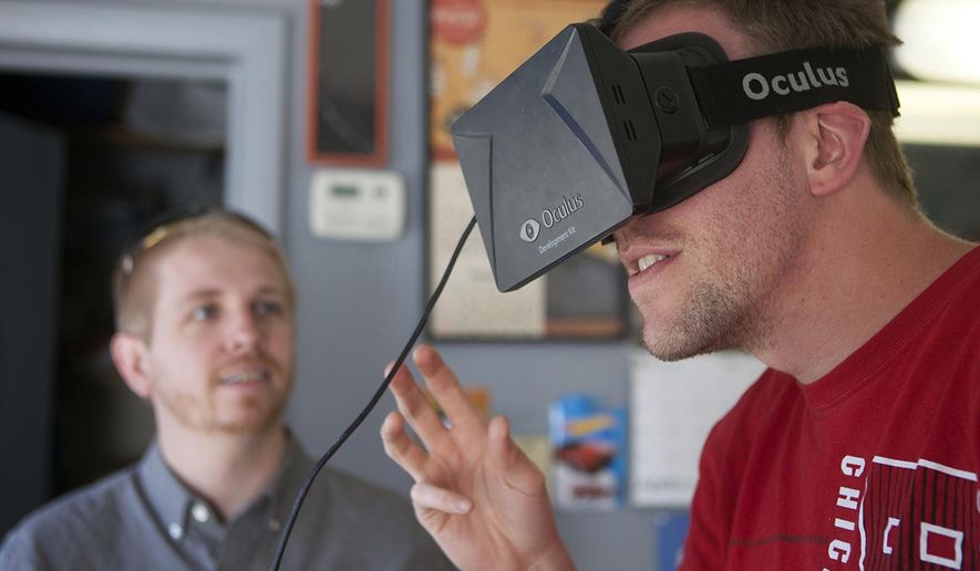 In this April 30, 2015, photo, Matt Groce of Monmouth, Ill., right, uses a pair of Occulus virtual reality goggles to try the video game “Children of Uum” as Rocky Mountain College of Art and Design video game art student and Galesburg native Ricky Davis looks on Thursday at Glory Days Corner Barber Shop In Galesburg, Ill. Davis is a member of 4th Axis Games, the development team for the game, which was previewed at the Denver Comic Con on May 23 through May 25. (Steve Davis/The Register-Mail via AP)