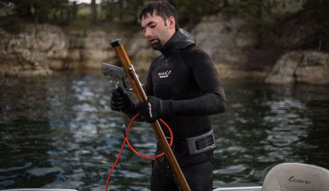 In this photo taken on Saturday, June 6, 2015, a competitor emerges from the water with his custom-made spear gun during the U.S. Freshwater Spearfishing Nationals at Keyhole Reservoir near Moorcroft, Wyo. (Ryan Dorgan/The Casper Star-Tribune via AP)