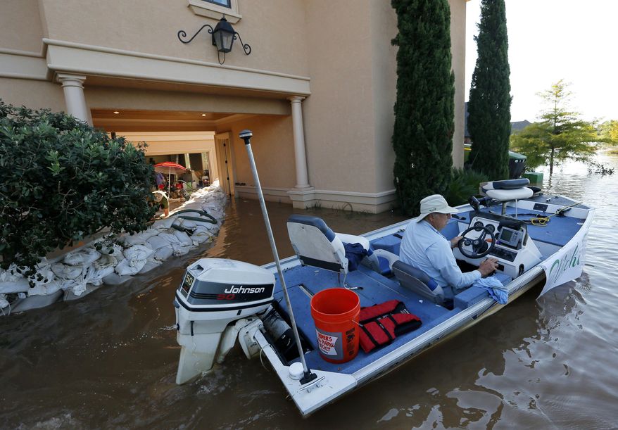 Rigby Hollingsworth boats past a family friend's home that is protected by sandbags from water caused by the flooding of the Red River, Wednesday, June 10, 2015, in Bossier City, La. (AP Photo/Jonathan Bachman)