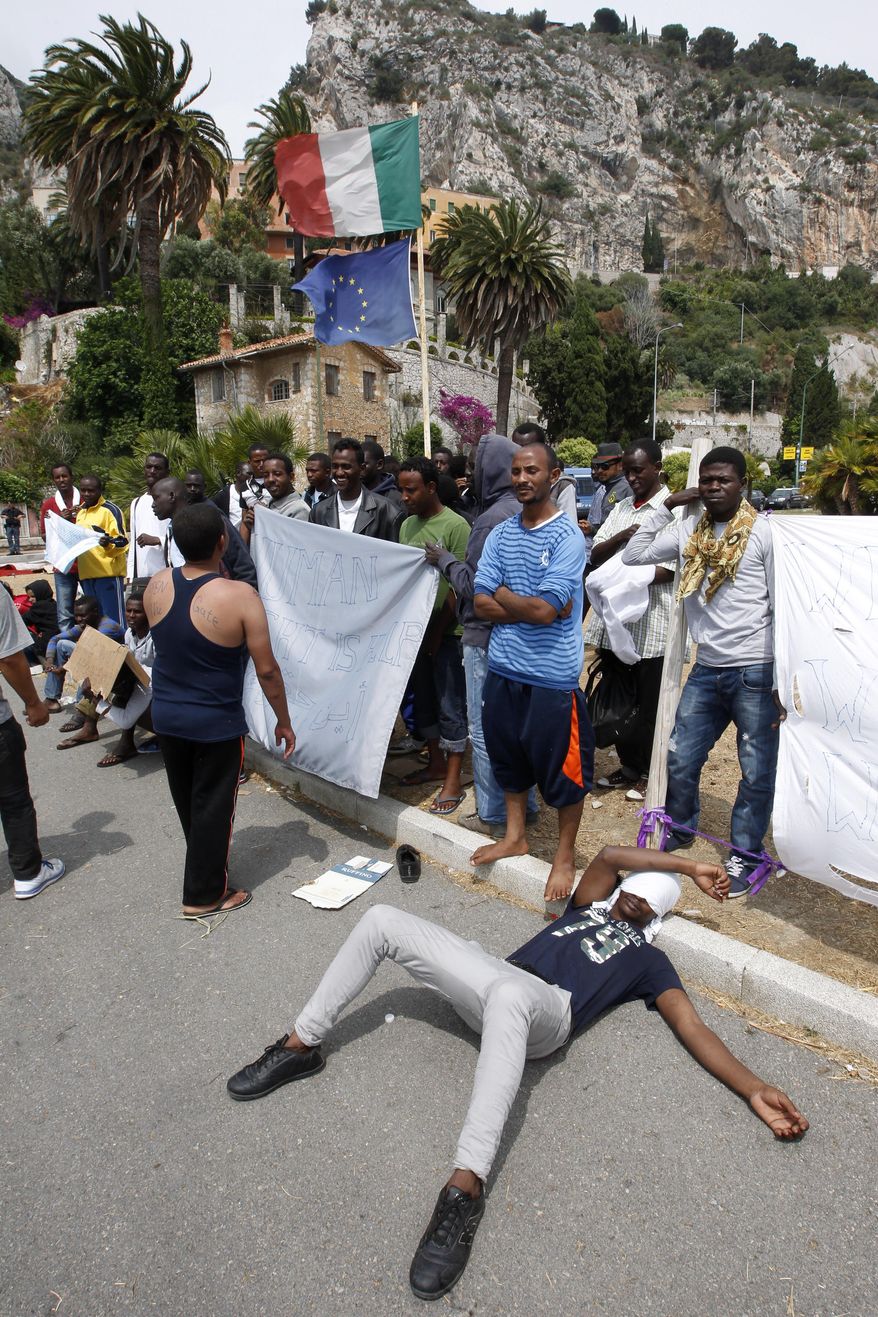 Migrants wait at the Franco-Italian border near Menton, southeastern France, Saturday, June 13, 2015. Some 150 migrants, principally from Eritrea and Sudan, attempted to cross the border from Italy into northern Europe, but have been blocked by French and Italian gendarmes. (AP Photo/Lionel Cironneau)