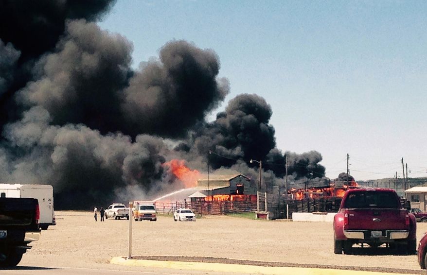 This Saturday, June 13, 2015 photo provided by Lori Ryan shows a fire burning at the Miles City Lovestock Commission Building in Miles City, Mont. Flames and black smoke poured from the stockyards which the livestock commission company says is one of the oldest in the region. No animals were inside the building and those that were outside were moved to safety. The building was destroyed. (Lori Ryan via AP)
