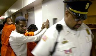Inmates Donnell Howard (foreground) and John Lawrence (background) wait handcuffed outside their cells while corrections officers search for contraband and weapons during a suprise search at the Washington DC Central Detention facility in Washington DC on Thursday, May 30, 2002. The unannounced searches take place at least once a year and are planned so as to not allow inmates time to dispose of the weapons. Inmates are required to have paperwork for items such as authorized medication. ( Gerald Herbert / The Washington Times )
