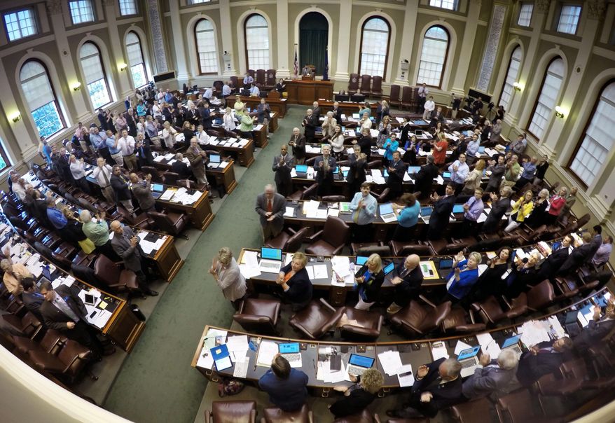 Members of the Maine House stand to acknowledge guests in attendance during a legislative session at the State House, Tuesday, June 16, 2015, in Augusta, Maine. Lawmakers have announced a budget agreement that they say will prevent a shutdown of state government. Democratic and Republican legislative leaders announced the bipartisan agreement late Monday night that includes tax cuts, investment in students and workers, property tax relief and welfare reform. (AP Photo/Robert F. Bukaty)