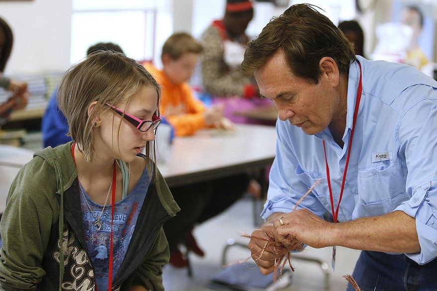 ADVANCE FOR USE SUNDAY, JUNE 21 AND THEREAFTER - In this May 12, 2015 photo, Elisabeth Symonds gets help from artist Wayne Trinklein of St. Peters, Mo., while she works with copper wire to create a tree at Whiteside Middle School in Belleville, Ill. Trinklein was showing the students how to work with wire along with show his own wire and rock sculptures as part of of the artist in residence program in area schools. Trinklein was in town showing his creations at the Art on the Square fair in downtown Belleville. (Steve Nagy /Belleville News-Democrat, via AP)