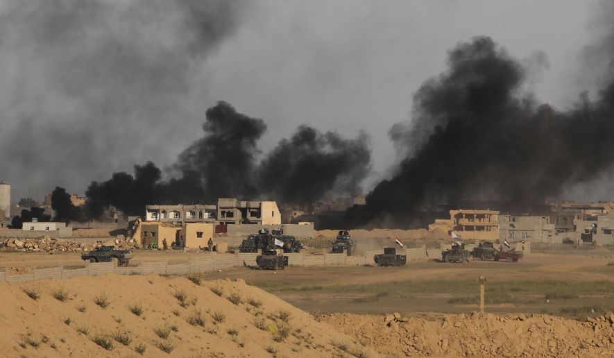 FILE - In this Friday, March 27, 2015 file photo, Iraqi security forces prepare to attack Islamic State extremist positions as smoke rises from central Tikrit, Iraq during clashes in the city, 130 kilometers (80 miles) north of Baghdad. (AP Photo/Khalid Mohammed)