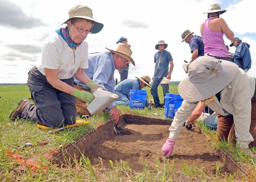 Cathie Volk, left, of Bismarck, and Mark Mitchell, back center, and Kim Field, right, work a one meter by two meter excavation unit at the Chief Looking's Village archaeological dig on Wednesday, June 17, 2015 in Bismarck, N.D. A nonprofit archaeological group from Denver is digging in North Dakota, looking for clues on how Mandan American Indians lived 500 years ago. (Tom Stromme/The Bismarck Tribune via AP)