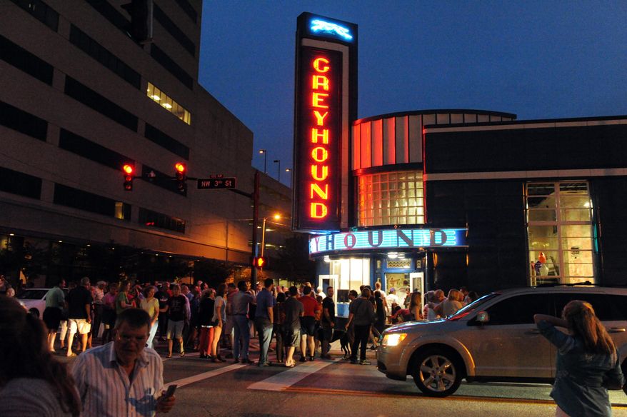 The neon lights are re-light as a large crowd gathers around the old Greyhound Station in Downtown Evansville, Ind., Thursday, June 18, 2015. A crowd of about 500 people cheered when the blue and amber neon lights were relit on the building's exterior, which is covered by two-toned blue porcelain enamel panels. (Jason Clark/Evansville Courier & Press via AP)