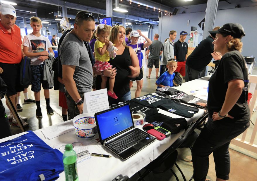 In this June 18, 2015, photo, John McNally of Lincoln, his daughter Katelynn, 2, and wife Heather look at T shirts for sale at the Support Blue booth outside TD Ameritrade Park in Omaha, Neb. The Support Blue campaign, that began as a way to show support for police officers, is now raising thousands of dollars for the causes championed by officer Kerrie Orozco, who was shot and killed in the line of duty last month. (AP Photo/Nati Harnik) (AP Photo/Nati Harnik)