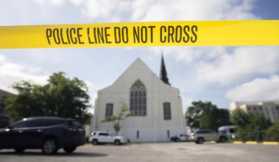 Police tape surrounds the parking lot behind the AME Emanuel Church as FBI forensic experts work the crime scene, Friday, June 19, 2015 where nine people where shot by Dylann Storm Roof, 21, on Wednesday in Charleston, S.C. The current brick Gothic revival edifice, completed in 1891 to replace an earlier building heavily damaged in an earthquake, was a mandatory stop for the likes of Booker T. Washington and the Rev. Martin Luther King Jr. Still, Emanuel was not just a church for the black community. (AP Photo/Stephen B. Morton, File)