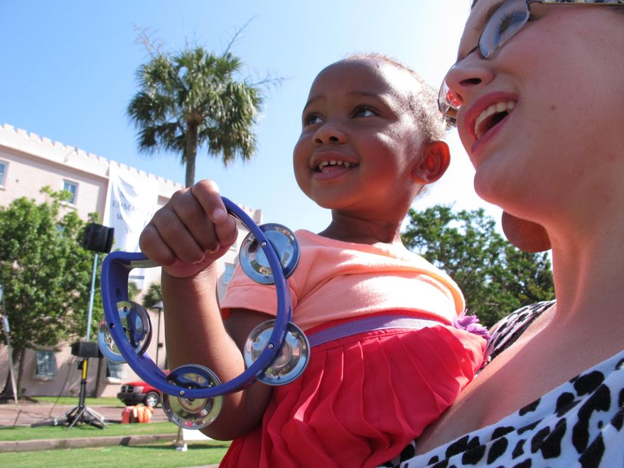 Michal Williams, 3, shakes her tambourine as she and big sister Quincy listen to the bells chiming from St. Matthew's Lutheran Church in Charleston, S.C., on Sunday, June 21, 2015. Churches around the city agreed to ring their bells at 10 a.m. in honor of nine people slain during a Bible study at Emanuel African Methodist Episcopal Church on Wednesday. (AP Photo/Allen G. Breed)