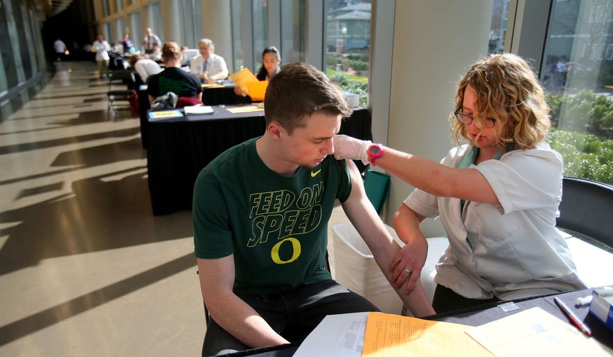 FILE - In this Monday, March 2, 2015 photo, pharmacist Jenna Wright administers the Meningitis B vaccine to University of Oregon freshman Drew Russert during a mass vaccination clinic at Matthew Knight Arena in Eugene, Ore. after an outbreak of meningococcemia, resulting in the death of a student. On Wednesday, June 24, 2015, a federal panel gave a weak endorsement to two new expensive meningitis shots, declining to recommend the vaccines for all teens and leaving the decision to parents and doctors. Students already get another meningitis vaccine that protects against more common strains. (AP Photo/The Register-Guard, Brian Davies)