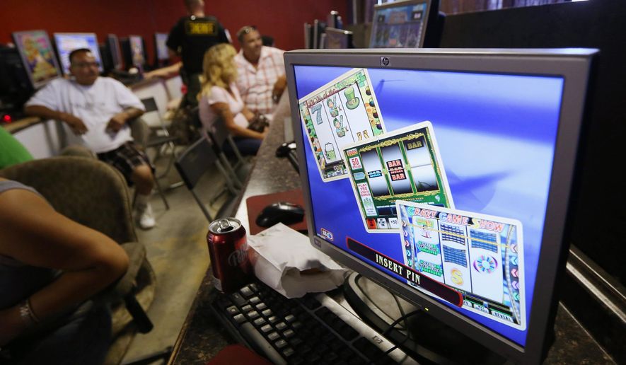 In this June 5, 2014, file photo, "sweepstakes" games are displayed on a computer screen as patrons wait to be questioned by a Sacramento County deputy sheriff during a code enforcement raid on the Silk and Stars in Sacramento, Calif. The State Supreme Court is set to decide Thursday, June 25, 2015, whether computerized "sweepstakes" games found inside Internet cafes are illegal slot machines. State officials have been cracking down on such businesses in recent years on the grounds they are illegal gambling dens. But the business owners say the sweepstakes, unlike slot machines, have predetermined outcomes and are not games of chance. (AP Photo/Rich Pedroncelli, File)