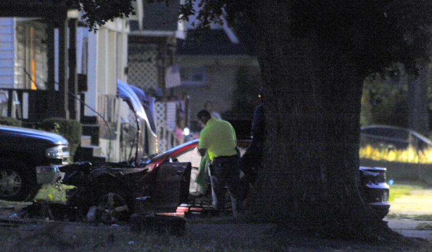 Detroit Police officers check out the damage to a car involved in a police chase on Wednesday, June 24, 2015 in Detroit. A driver accelerated to more than 70 mph on a residential street in Detroit while fleeing officers before striking and killing two young children and injuring three other children and an adult, police said. (Steve Perez/Detroit News via AP) DETROIT FREE PRESS OUT; HUFFINGTON POST OUT