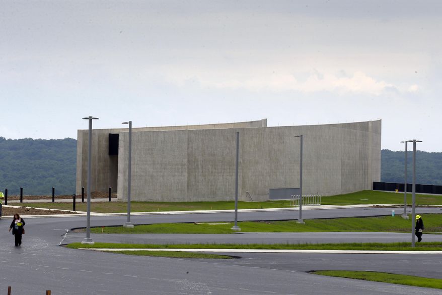Reporters walk past the visitors center building at the Flight 93 National Memorial, in Shanksville, Pa. during a press tour of the ongoing construction, Thursday, June 25, 2015. The $26 million visitor center complex is scheduled to be dedicated and open to the public Sept. 10, 2015, a day before the 14th anniversary of the terror attacks during which passengers caused the hijacked airliner to crash there. (AP Photo/Keith Srakocic)
