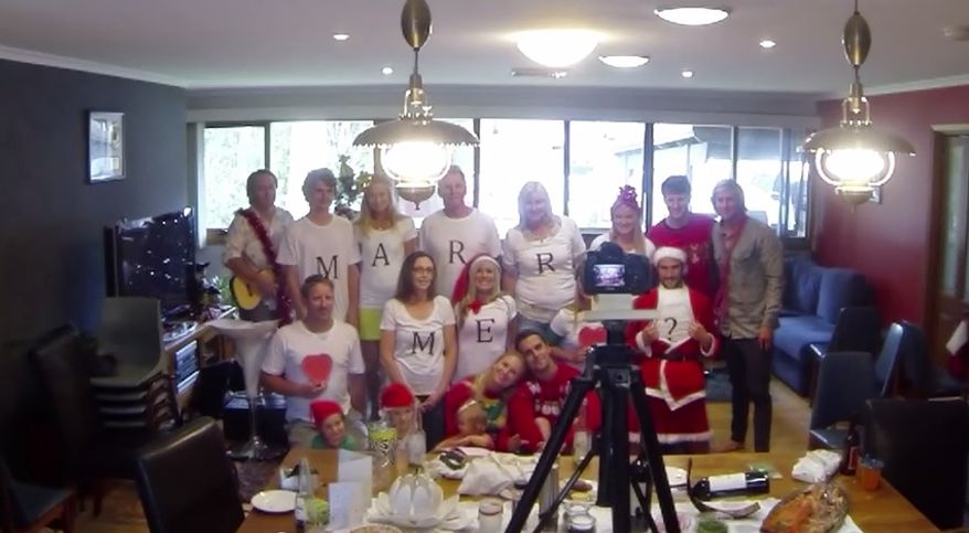 Merry X-mas Proposal: The family lines up for a Christmas video, complete with T-shirts that spell out "Merry X-Mas." But while the video is recording, everyone rearranges themselves to spell out the real message! (Photo: YouTube/Kerry Langdon Down)