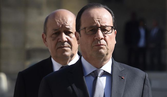 French President Francois Hollande and Defence Minister Jean-Yves Le Drian, behind, review troops during a military ceremony at the Hotel des Invalides in Paris, France, Thursday, June 25, 2015. (Dominique Faget, Pool via AP)
