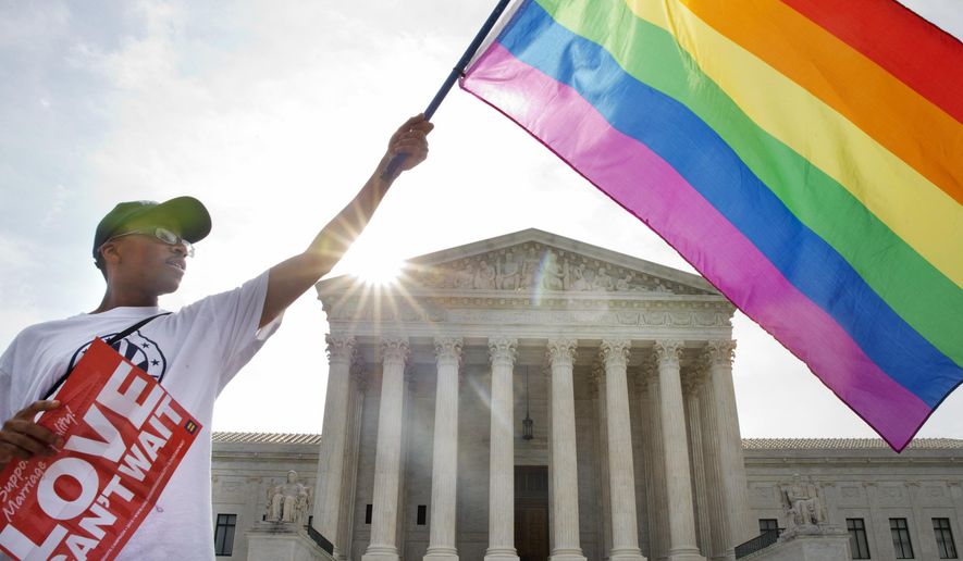 Carlos McKnight of Washington, waves a flag in support of gay marriage outside of the Supreme Court in Washington, Friday June 26, 2015. A major opinion on gay marriage is among the remaining to be released before the term ends at the end of June.  (AP Photo/Jacquelyn Martin)