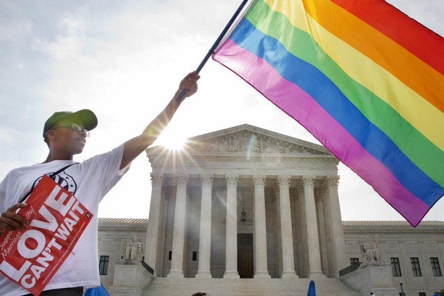 Carlos McKnight of Washington, waves a flag in support of gay marriage outside of the Supreme Court in Washington, Friday June 26, 2015. A major opinion on gay marriage is among the remaining to be released before the term ends at the end of June.  (AP Photo/Jacquelyn Martin)