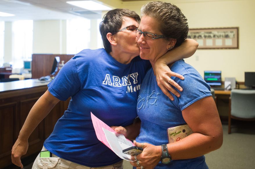 Traci Bliss Panzner kisses Julie Ann Lake as they wait to receive their marriage license after the U.S. Supreme Court ruling in favor of same sex marriage at the Bay County Building on Friday June 26, 2015 in May City, Mich. Michigan Attorney General Bill Schuette says he will "honor, respect and uphold" the decision by the U.S. Supreme Court that overturned the state's ban on same-sex marriage. (Yfat Yossifor/The Bay City Times via AP) LOCAL TELEVISION OUT; LOCAL INTERNET OUT
