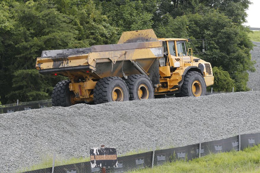 A trucks hauls coal ash from one retention pond to a permanent pond at the Dominion Power's Possum Point Power Station in Dumfries, Va., Friday, June 26, 2015. The company is moving coal ash from several ponds to one lined pond. (AP Photo/Steve Helber)
