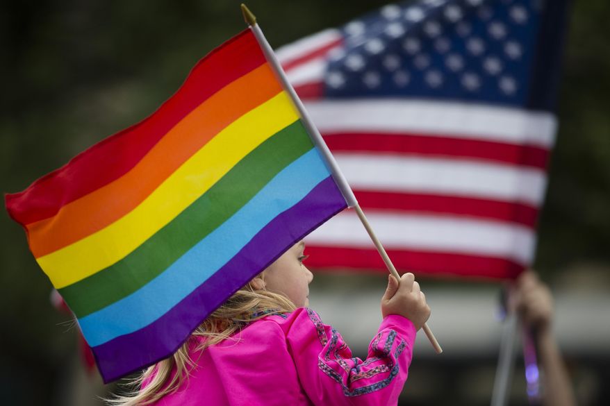 Keira Phair, of Westchester, Ohio, holds a rainbow flag during the Cincinnati Pride parade, Saturday, June 27, 2015, in Cincinnati. On Friday, the U.S. Supreme Court ruled that same-sex couples have the right to marry nationwide. (AP Photo/John Minchillo)
