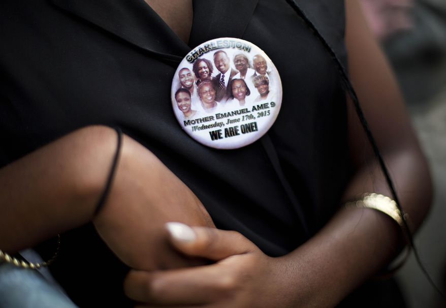 Krislynn Rambert, of Charleston, S.C., wears a button in memory of the victims of last week&#39;s mass shooting while waiting on line to enter Sen. Clementa Pinckney&#39;s funeral service, Friday, June 26, 2015, in Charleston, S.C. President Barack Obama will deliver the eulogy at Pinckney&#39;s funeral at a nearby college arena. (AP Photo/David Goldman)