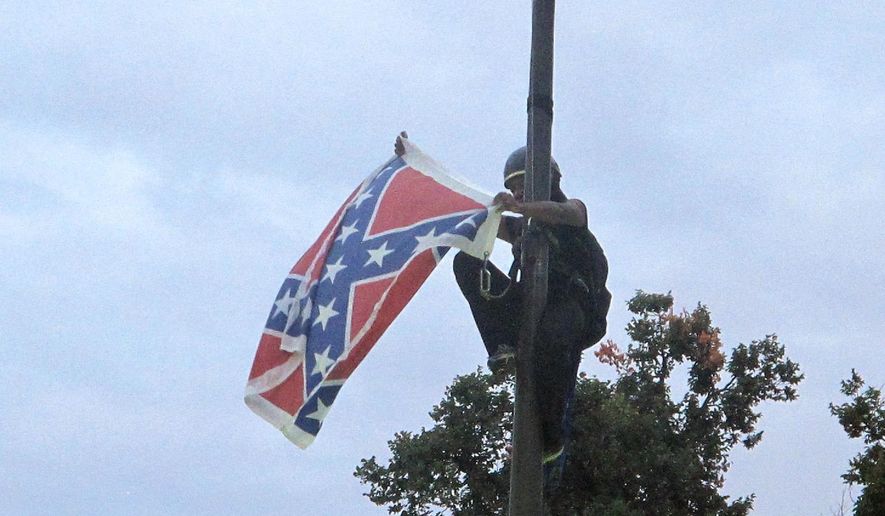 Bree Newsome of Charlotte, N.C., removes the Confederate battle flag at a Confederate monument at the Statehouse in Columbia, S.C., on Saturday, June, 27, 2015. She was taken into custody when she came down. The flag was raised again by Capitol workers about 45 minutes later. (AP Photo/Bruce Smith) ** FILE **