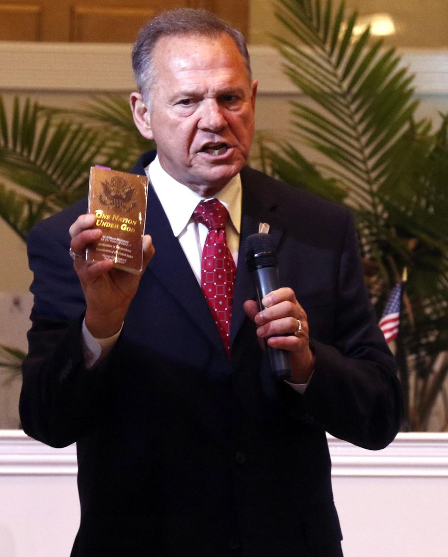 Alabama Supreme Court Chief Justice, Roy Moore, holds a copy of the Constitution as he speaks to the congregation of Kimberly Church of God, Sunday, June 28, 2015, in Kimberley, Ala. Moore lashed out at the U.S. Supreme Court decision which legalized same-sex marriage nationwide, saying said the decision was against the laws of nature. (AP Photo/Butch Dill)