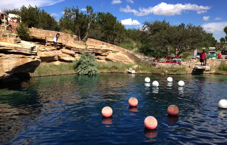 This Saturday, June 6, 2015 photo shows a boy leaping into the water at Blue Hole State Park in Santa Rosa, N.M. Blue Hole is part of the New Mexico Tourism Department's "New Mexico True" campaign, an effort aimed at drawing more tourists to the state. Gov. Susana Martinez on Monday, June 29, 2015, announced statewide visitor numbers for 2014 marked another record-breaking year. (AP Photo/Susan Montoya Bryan)